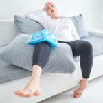 person sitting on a coudh with ice pack on knee